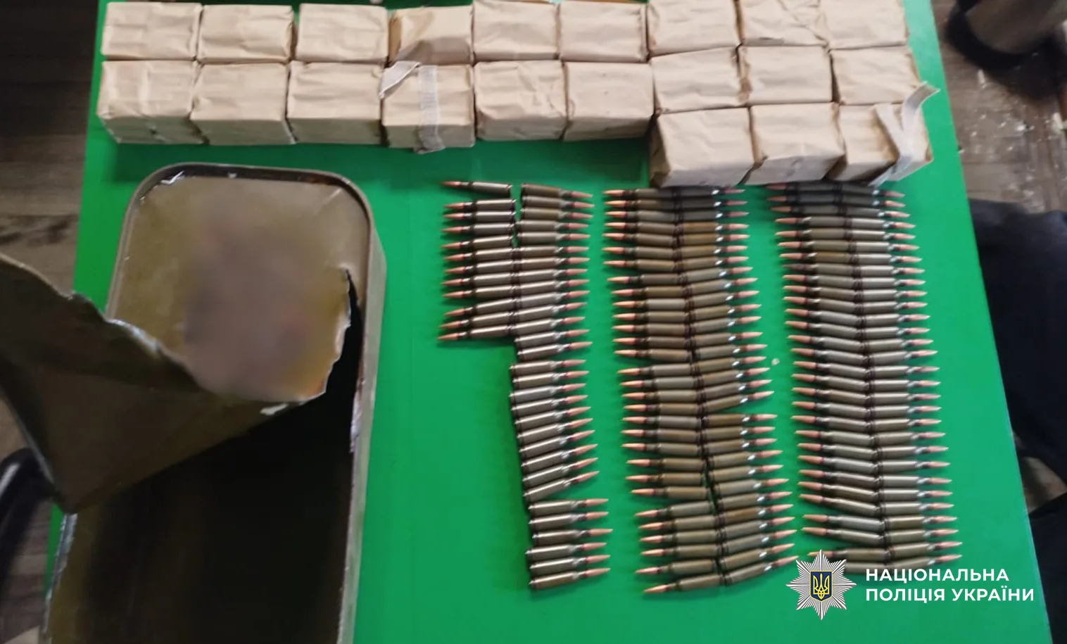 Сотні набоїв, розкладені рядами на зеленому столі, поруч пачки в паперовій упаковці та розкритий металевий ящик