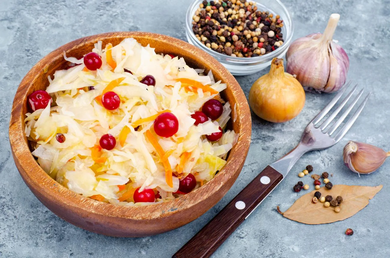Sauerkraut with red cranberries in wooden bowl. Studio Photo