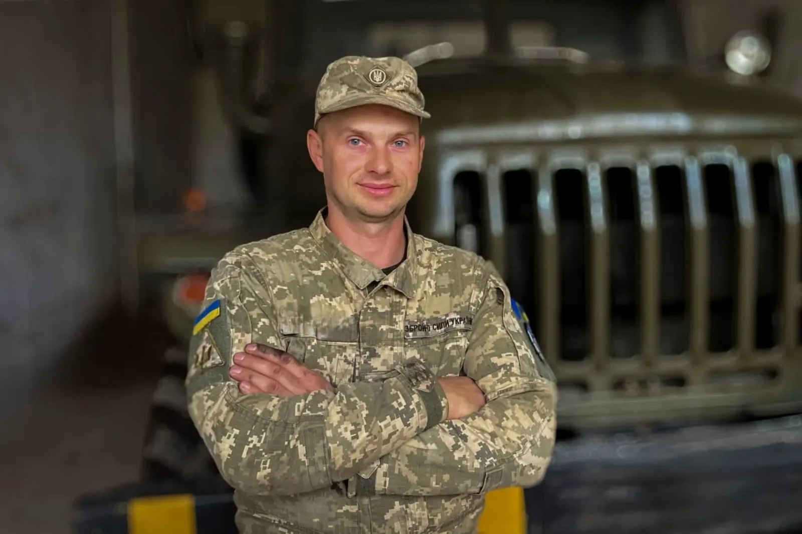 Військовий у формі схрестив руки на грудях і посміхається