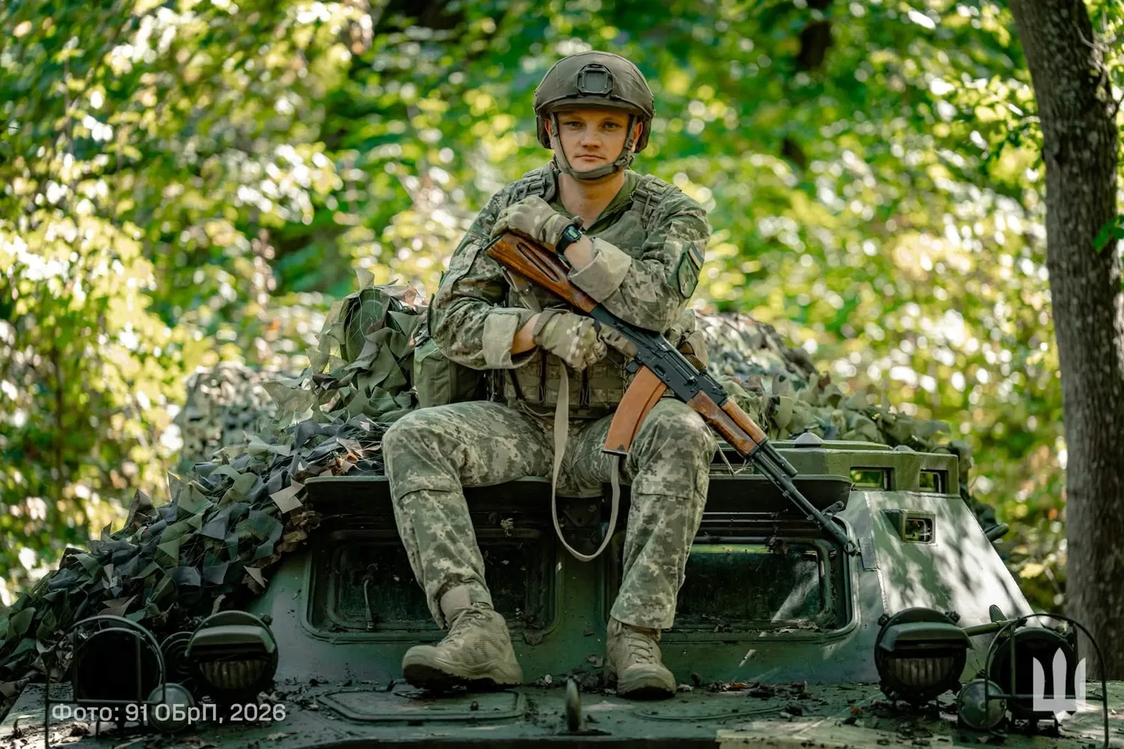 Військовий у засобах захисту зі зброєю в руках сидить на броні