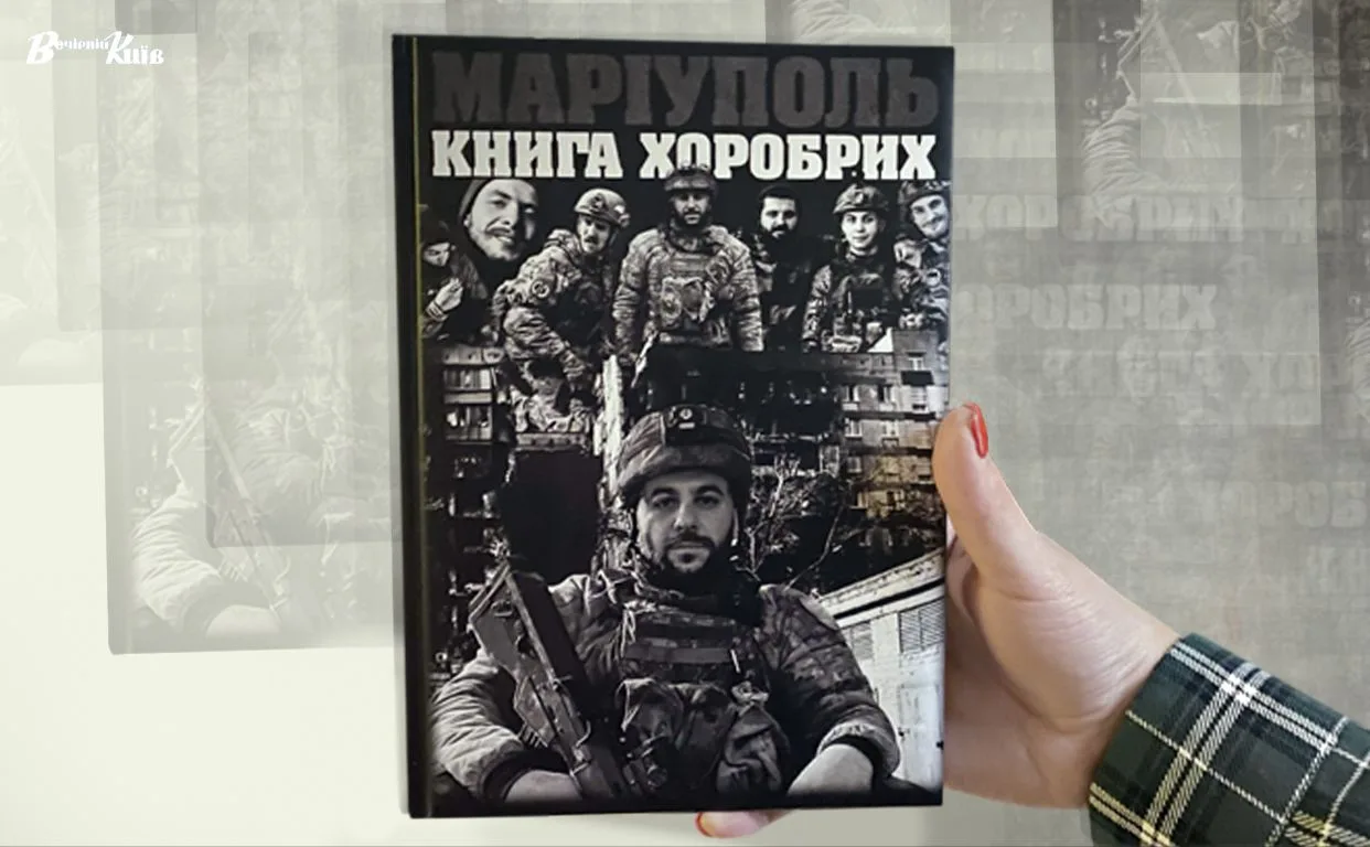 Обкладинка книги «Маріуполь. Книга хоробрих», яку тримають у руці. На чорно-білій обкладинці — колаж із портретів українських військових у формі та спорядженні на тлі міської забудови.