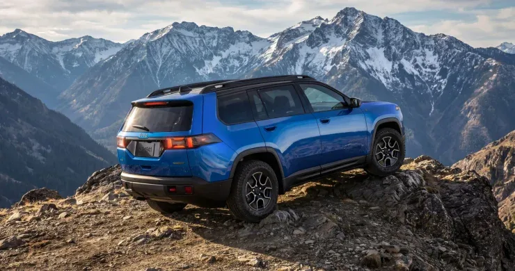 Синий внедорожник Jeep Cherokee Trailhawk стоит на скалистом горном склоне
