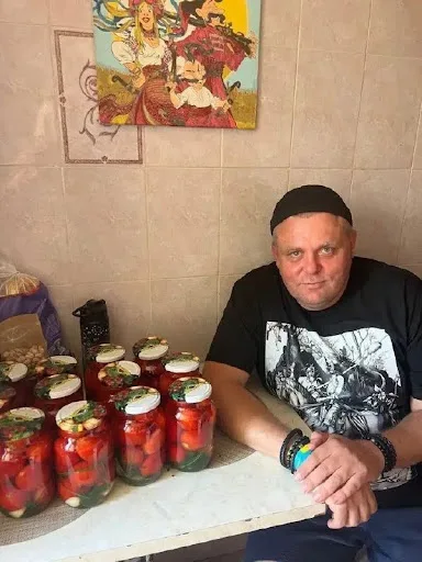 Чоловік сидить за столом поруч із закрутками