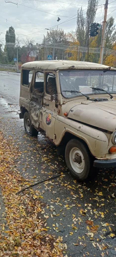 Пошкоджений бежевий позашляховик стоїть на мокрій міській дорозі. На лівому боці кузова видно численні пошкодження й вм’ятини, вибите бокове скло та сліди ударів.