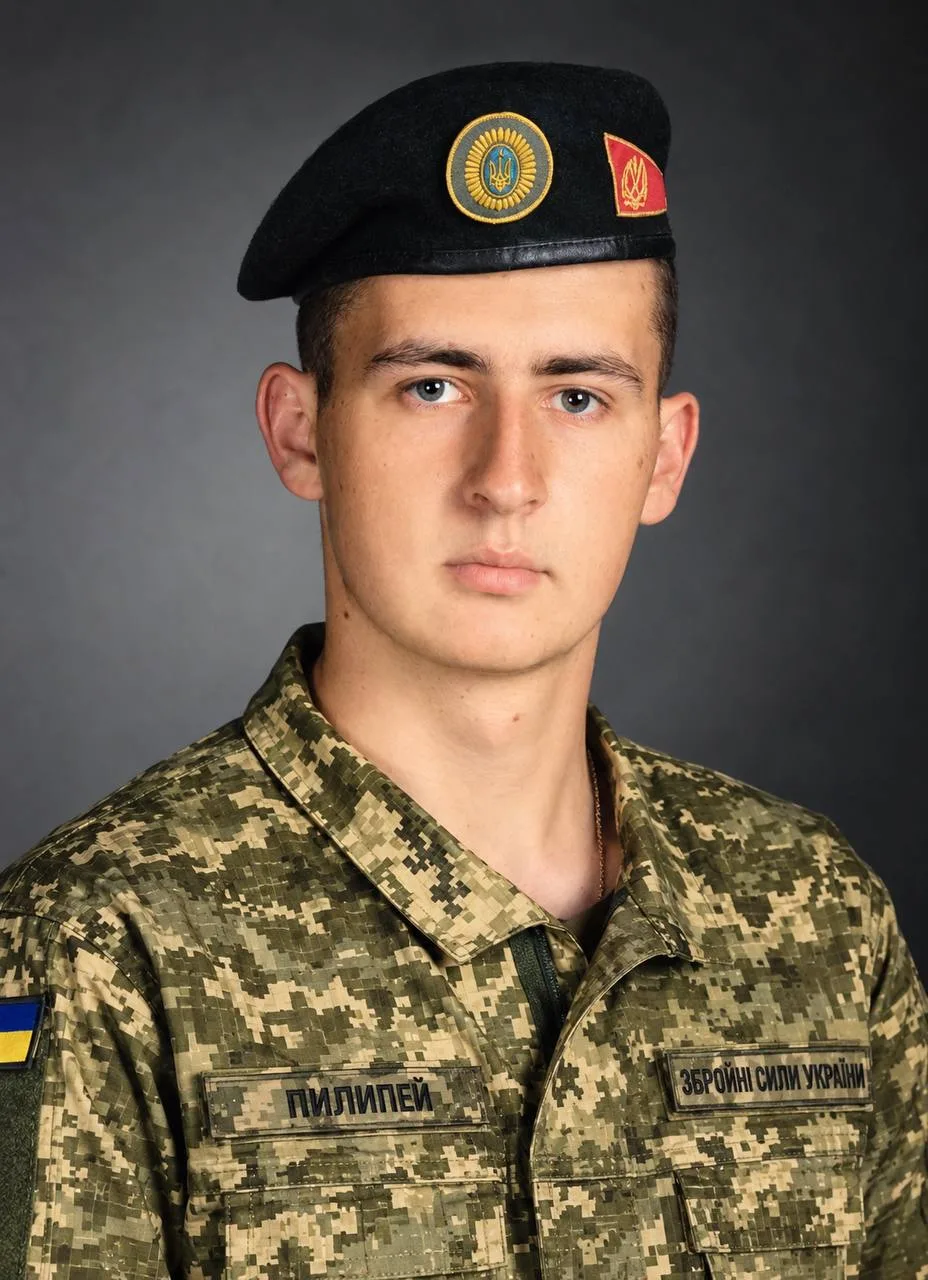Портретне фото військового Володимира Пилипея під час строкової служби. Чоловік має коротке темне волосся й сірі очі. Він вдягнений у форму з піксельним камуфляжем і чорний берет. На формі — ідентифікатори на липучках із прізвищем «Пилипей» та написом «Збройні сили України». Фото з архіву сімʼї