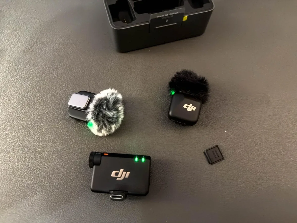 Передатчики DJI Mic Mini с ветрозащитами рядом с приёмником на столе