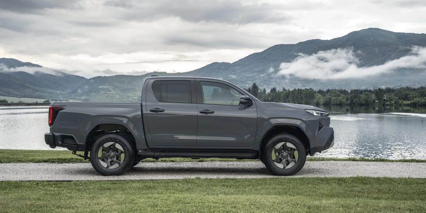 Toyota Hilux BEV в профиль на фоне озера и гор