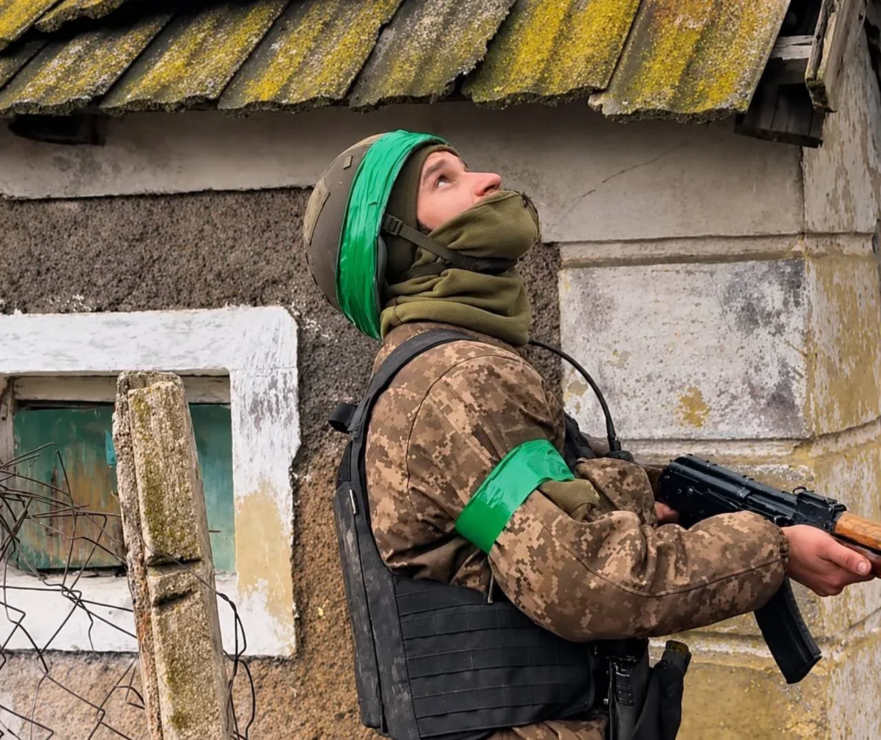 Військовий з автоматом у шоломі і бронежилеті дивиться в небо