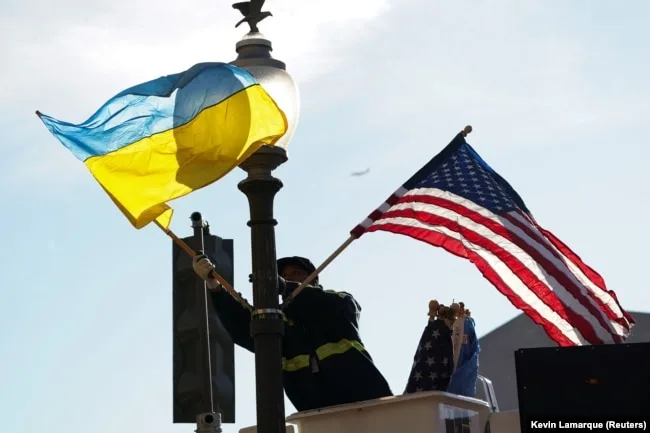 Чоловік встановлює українські та американські прапори вздовж Пенсільванія-авеню, що веде до Капітолію перед візитом президента України Володимира Зеленського, Вашингтон, США, 21 грудня 202 року