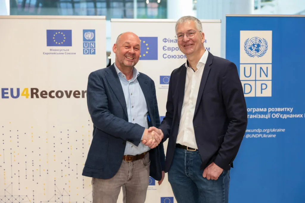 Представники ЄС і ПРООН потискають руки на тлі банерів EU4Recovery під час презентації другої фази програми в Дніпрі у травні 2026 року.